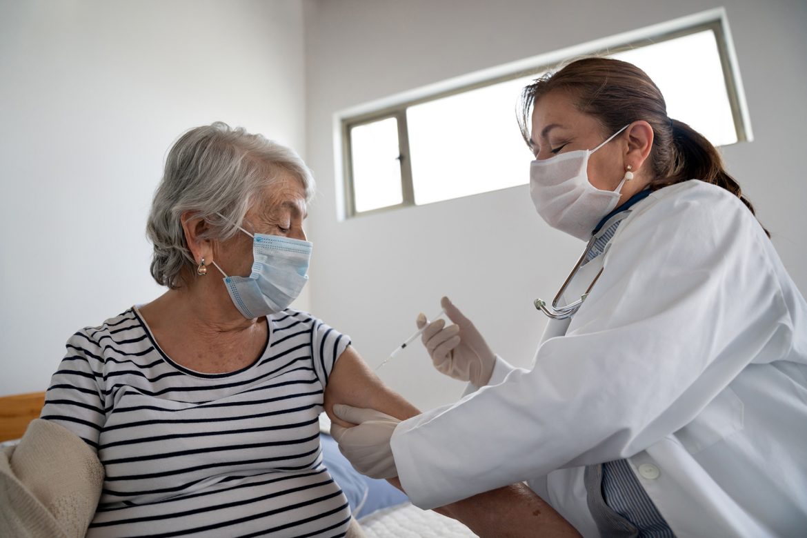An elderly woman receiving an injection from a health professional