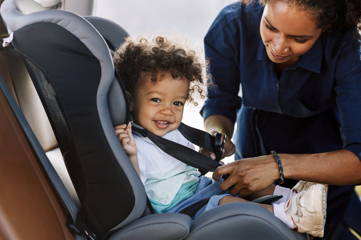 A mother straps her baby into a car seat