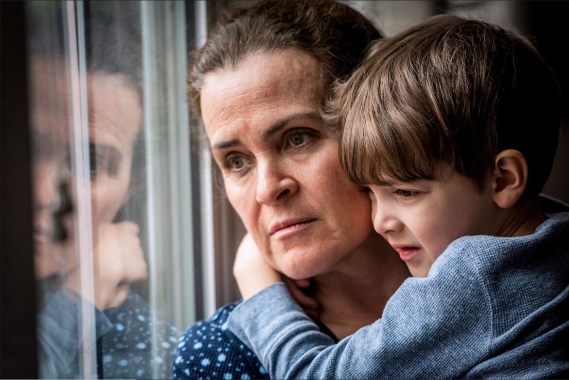 Pensive woman holds child and looks out window