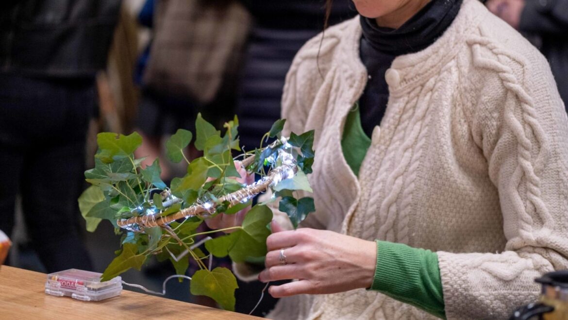 A person wraps fairy lights around branches