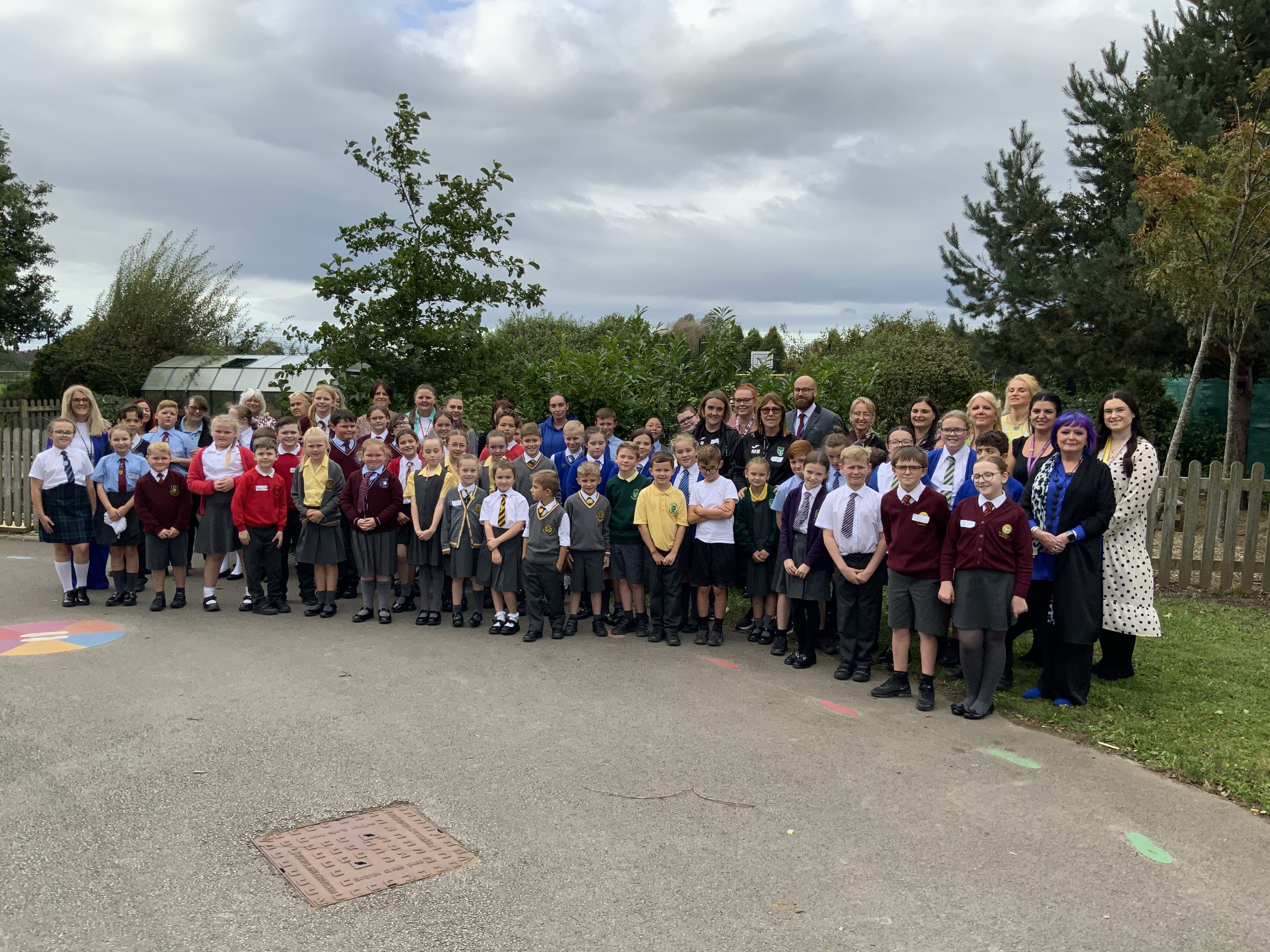 Large group of teachers and pupils stand together for a group image