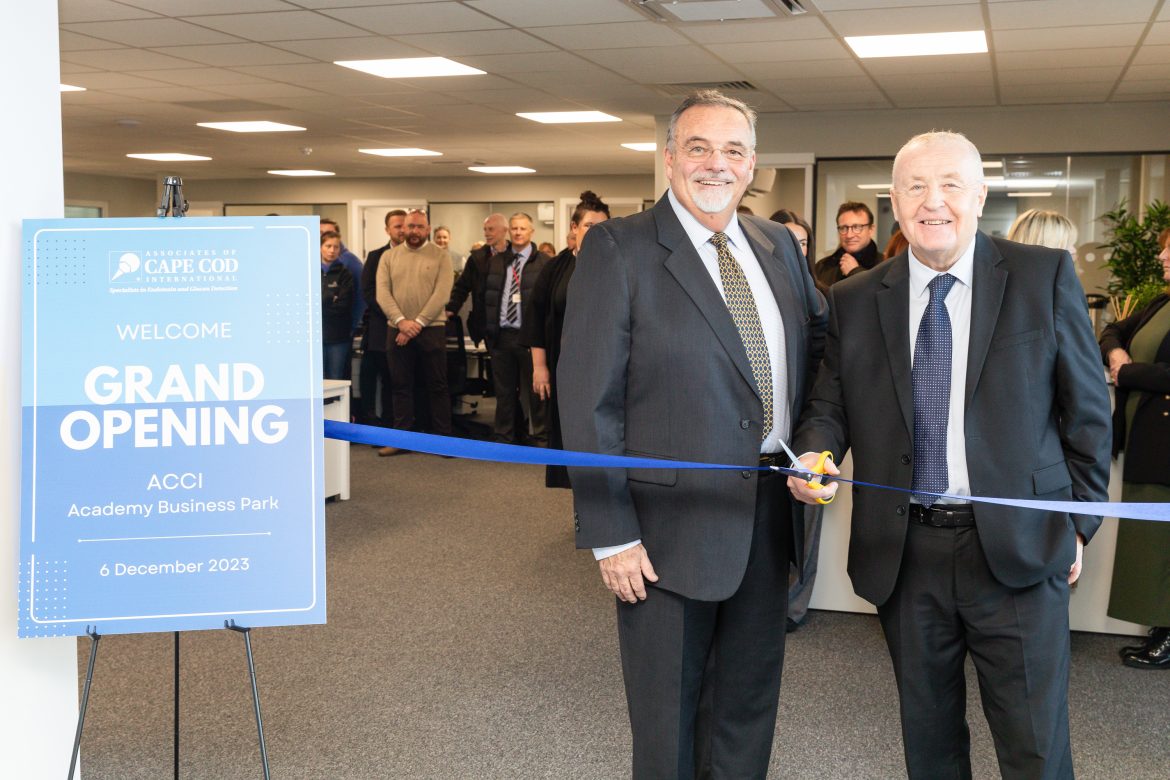 Two men dressed in suits cut a ribbon
