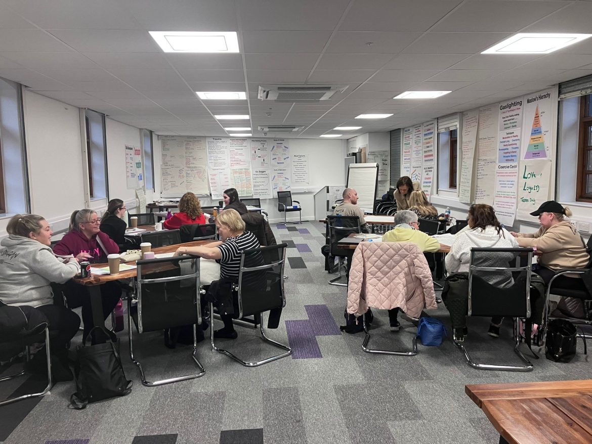 A group of people sit at tables at a training day.