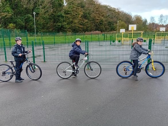 20231114_102716 Three children on bikes with helmets in the school playground.