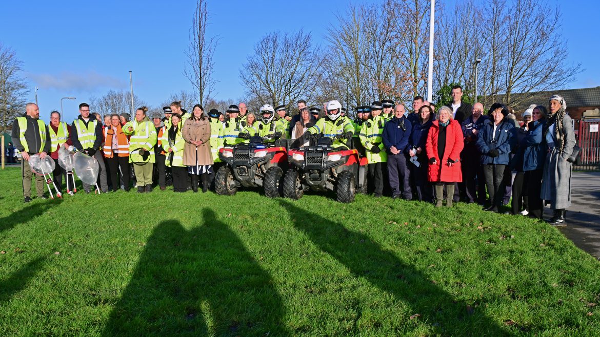 A large group photo comprising police officers in yellow high vis jackets, litter picking volunteers and other members of the community. At the front of the group are two officers on quad bikes.