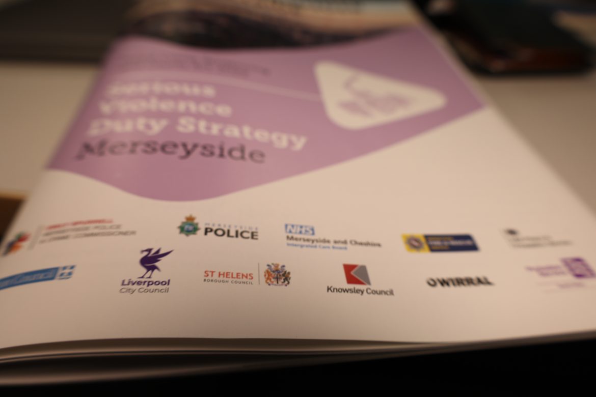 Closeup of a booklet with various organisations logos, including Knowsley Council, Liverpool City Council and the police.