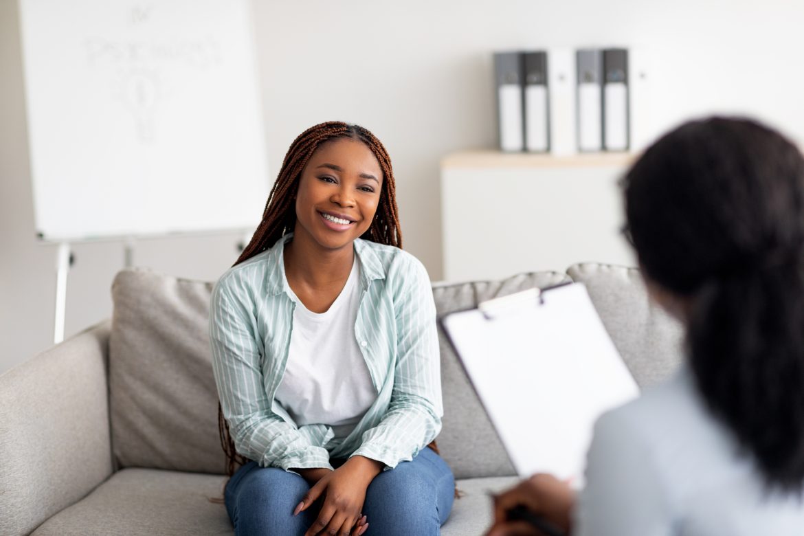 A women attends a meeting. She sits on a couch.