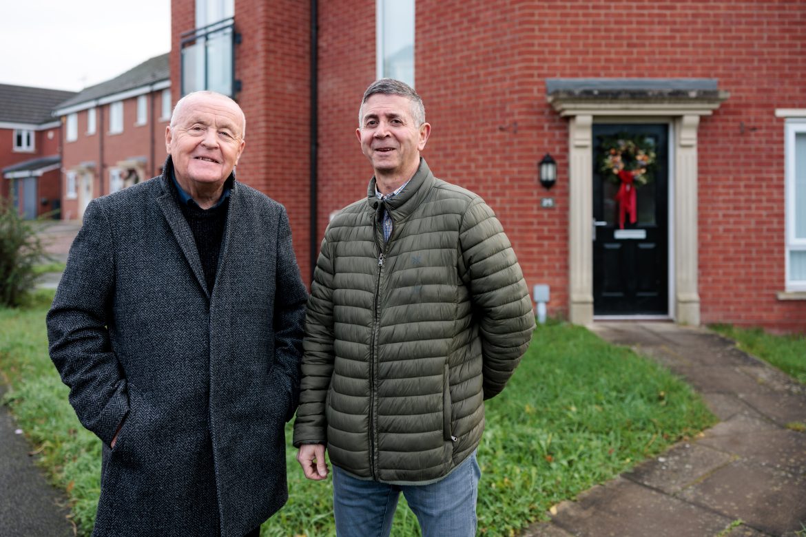 2 men standing in front of a house