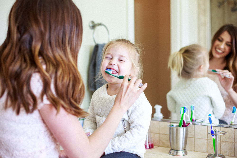A parent helping a child to brush their teeth